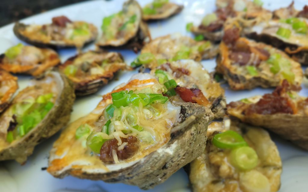 grilled steamed oysters with toppings of green onion, backon, cheese, and rockafeller sauce