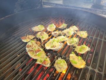 oysters on the grill with toppings of green onion, and bacon