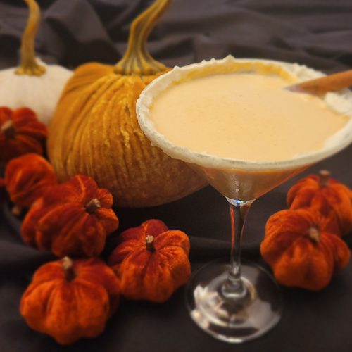 pumpkin spice martini sits in front of straw pumpkin decorations