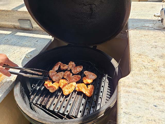 placing wings on a big green egg with grill grates
