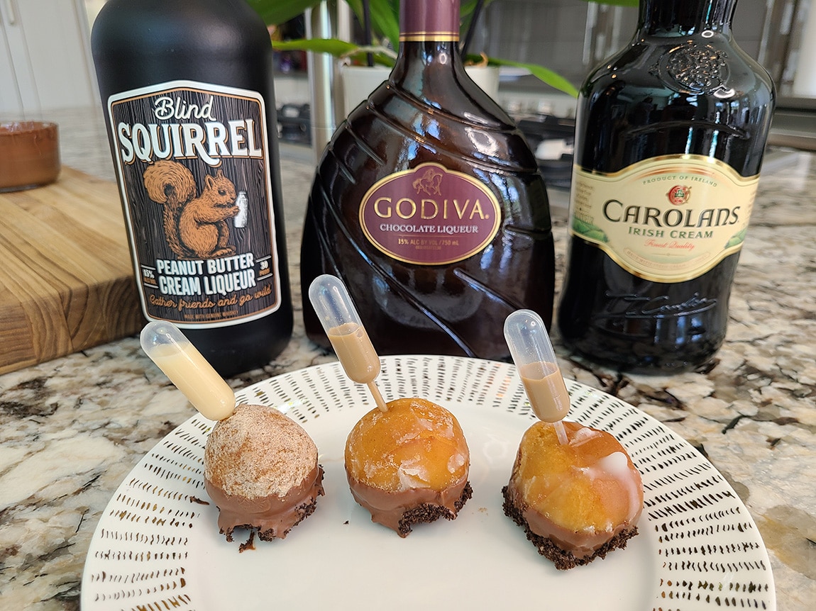 Dunkin Donut Holes dipped in melted chocolate, crushed oreos with pipettes filled with liquor
