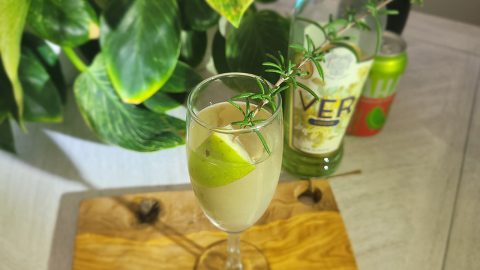 champagne glass with prossecco, Ver liqueur, ginger soda garnished with an apple and sprig of rosemary
