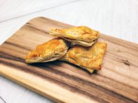 Curry puff pastry bites stacked on a wooden board