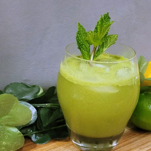 green cocktail with mint leaves with limes, lemons, and matcha