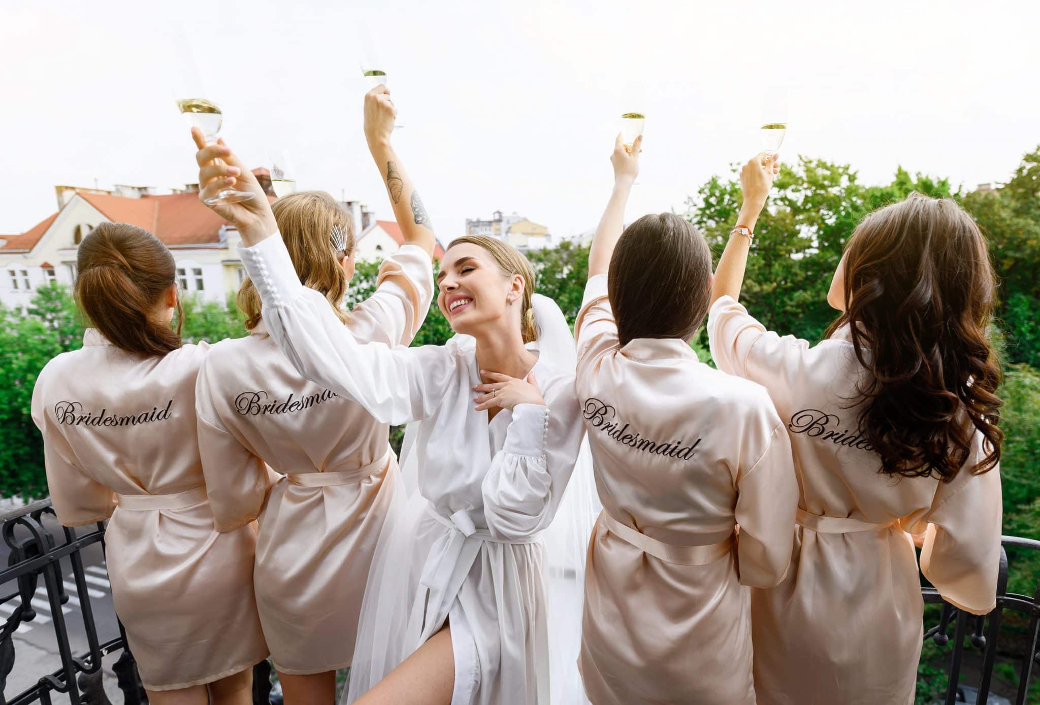 Happy Bachelorettes in wedding silk robes toasting the bride
