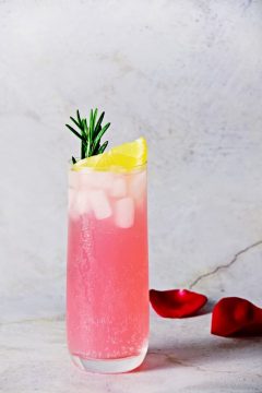 pink drink with ice garnished with lemon and rosymary