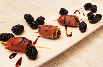 3 prosciutto wrapped appetizers on a white plate with blackberry garnishes