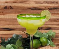 Midori Melon Margarita with lime in front of a wooden board