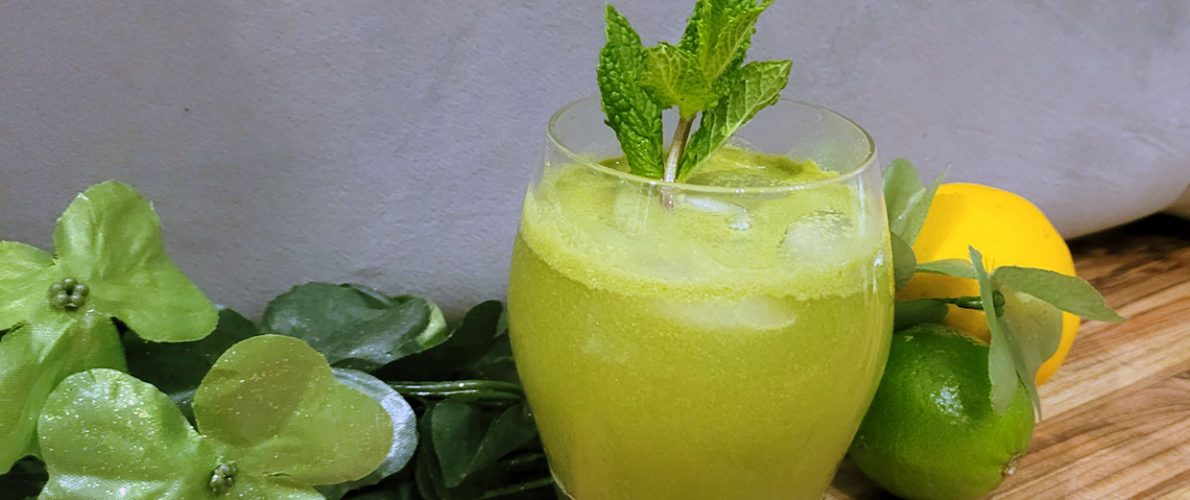 green cocktail with mint leaves with limes, lemons, and matcha