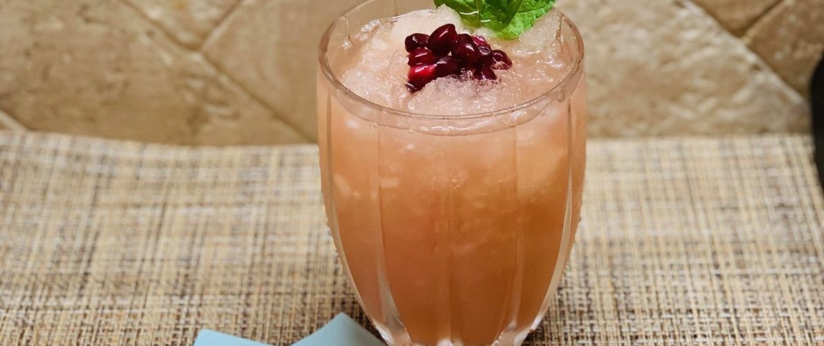 Cocktail with rose wine, vodka, citrus juices, rushed ice and pomegranate pearls.